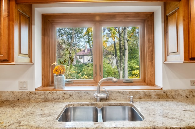 kitchen with a healthy amount of sunlight, light stone countertops, and sink