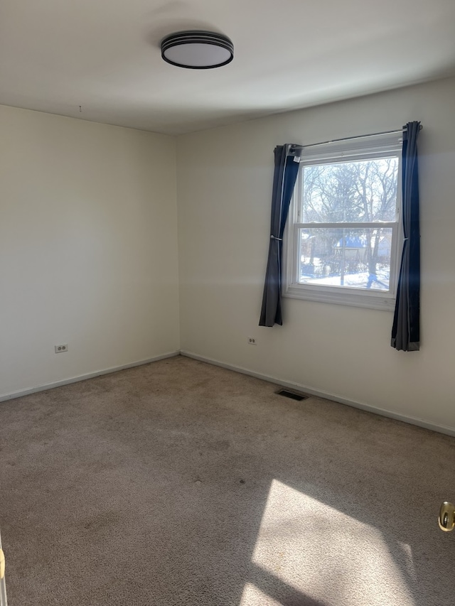 empty room with carpet flooring, visible vents, and baseboards