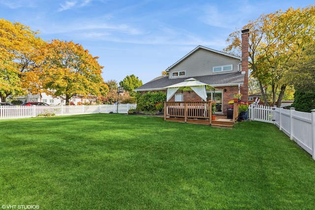 rear view of property featuring a fenced backyard, a wooden deck, a lawn, and a gazebo