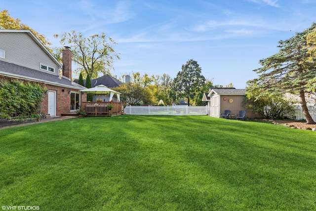 view of yard with a fenced backyard, an outbuilding, a wooden deck, and a gazebo