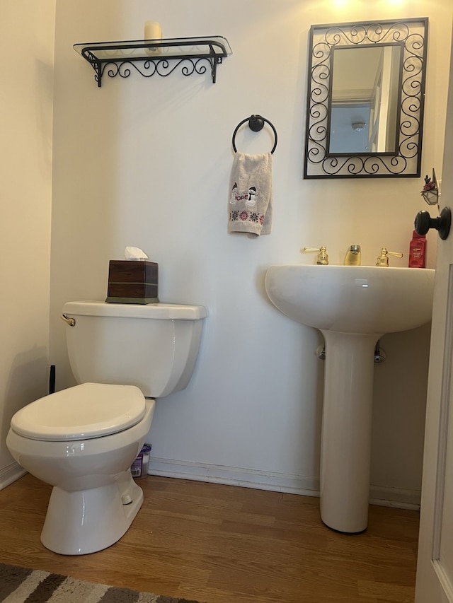 bathroom with toilet, baseboards, and wood finished floors