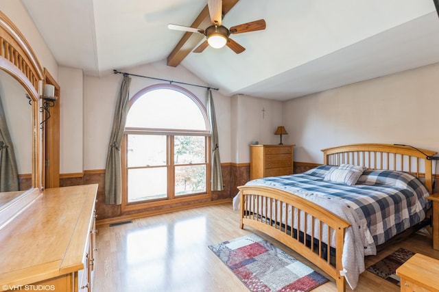 bedroom featuring visible vents, wainscoting, lofted ceiling with beams, ceiling fan, and light wood-style floors