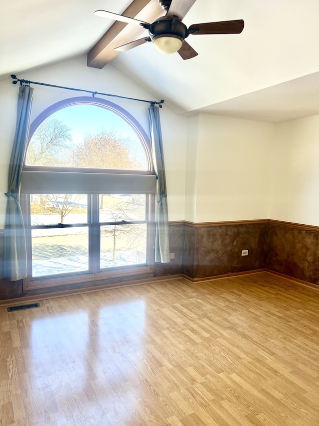 empty room featuring a healthy amount of sunlight, wainscoting, and light wood-style flooring