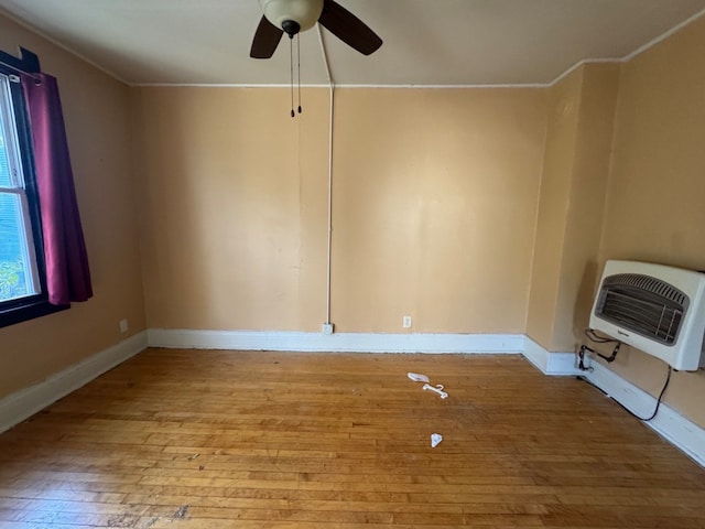 empty room with crown molding, heating unit, light wood-type flooring, and ceiling fan