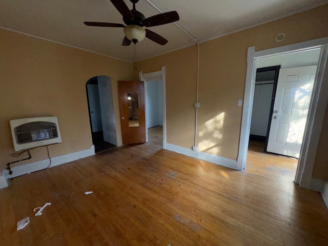 unfurnished living room with ceiling fan, heating unit, and light wood-type flooring