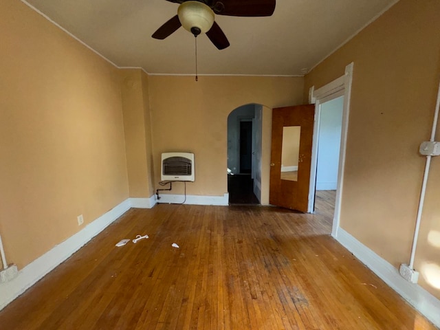 empty room featuring hardwood / wood-style floors, heating unit, and ceiling fan