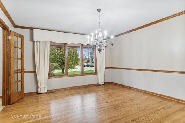 unfurnished dining area featuring hardwood / wood-style flooring, an inviting chandelier, and crown molding