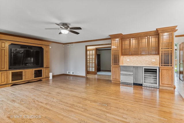 unfurnished living room with light hardwood / wood-style floors, ornamental molding, and beverage cooler