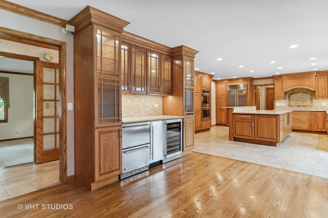 kitchen with a center island, beverage cooler, stainless steel appliances, and light wood-type flooring