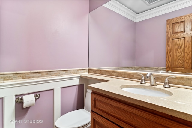 bathroom featuring tasteful backsplash, crown molding, vanity, and toilet