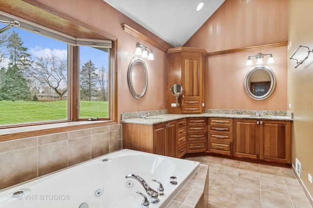 bathroom featuring tile patterned floors, vanity, tiled tub, and vaulted ceiling