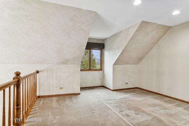 bonus room with light colored carpet and vaulted ceiling