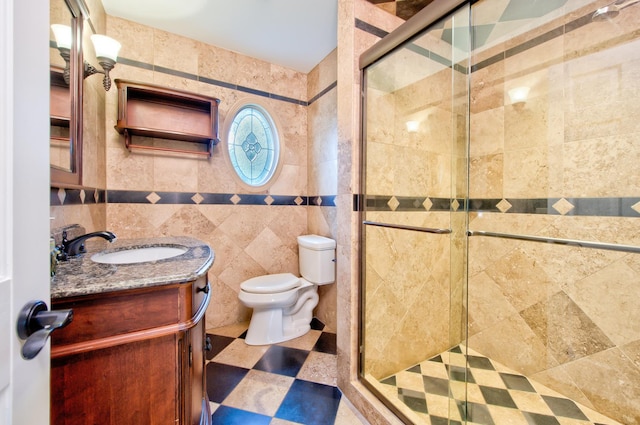 bathroom with tile walls, an enclosed shower, vanity, and toilet