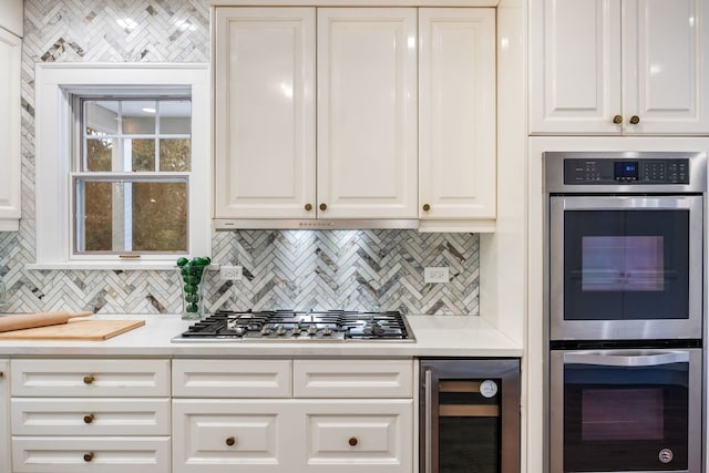 kitchen featuring stainless steel appliances, white cabinetry, backsplash, and wine cooler