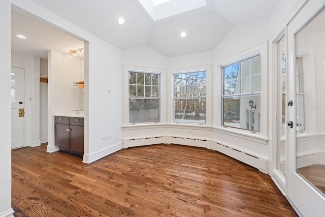 unfurnished sunroom featuring a baseboard heating unit and vaulted ceiling with skylight