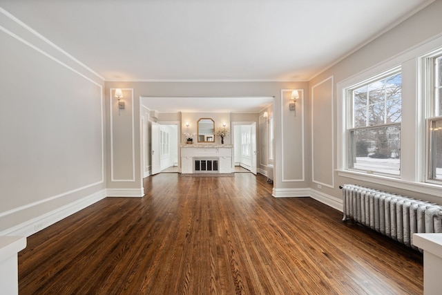 unfurnished living room featuring dark hardwood / wood-style flooring, radiator heating unit, crown molding, and a fireplace