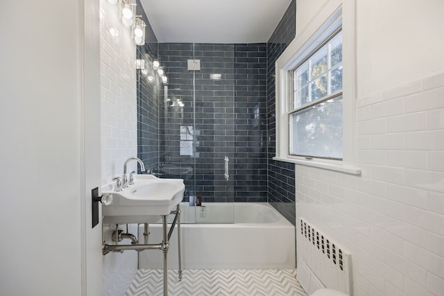 bathroom featuring tile walls, tiled shower / bath, radiator heating unit, and sink