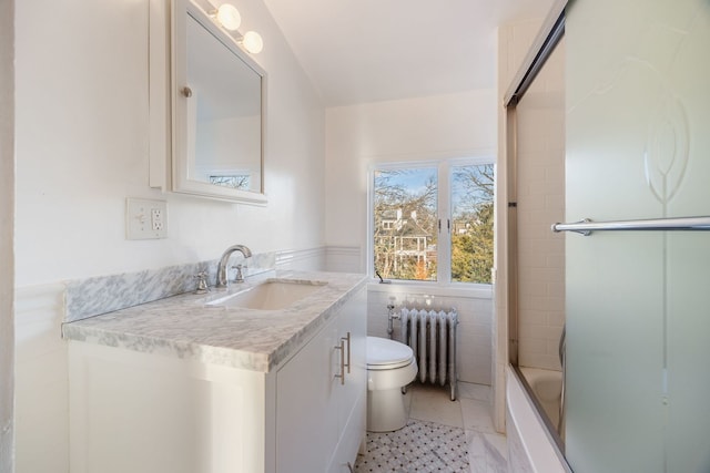 full bathroom featuring toilet, tile patterned flooring, radiator, combined bath / shower with glass door, and vanity