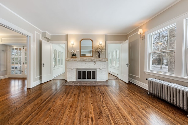 unfurnished living room featuring radiator, a fireplace, and dark wood-type flooring