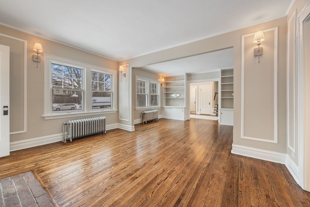 unfurnished living room with radiator, dark hardwood / wood-style flooring, and built in shelves