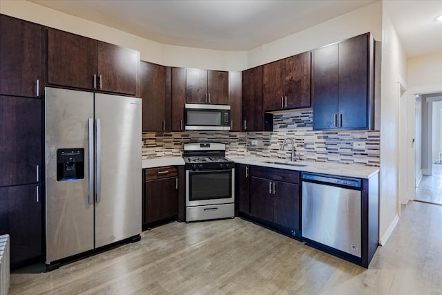 kitchen featuring stainless steel appliances, tasteful backsplash, light hardwood / wood-style floors, and sink