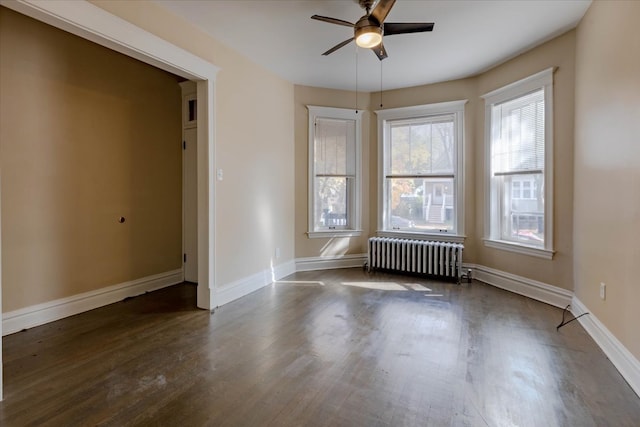 empty room featuring ceiling fan, radiator heating unit, and dark hardwood / wood-style floors