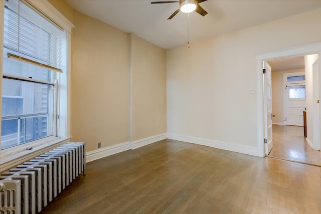 unfurnished room with ceiling fan, radiator heating unit, and hardwood / wood-style flooring