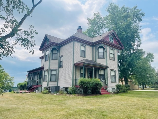 view of side of home with a yard and central AC