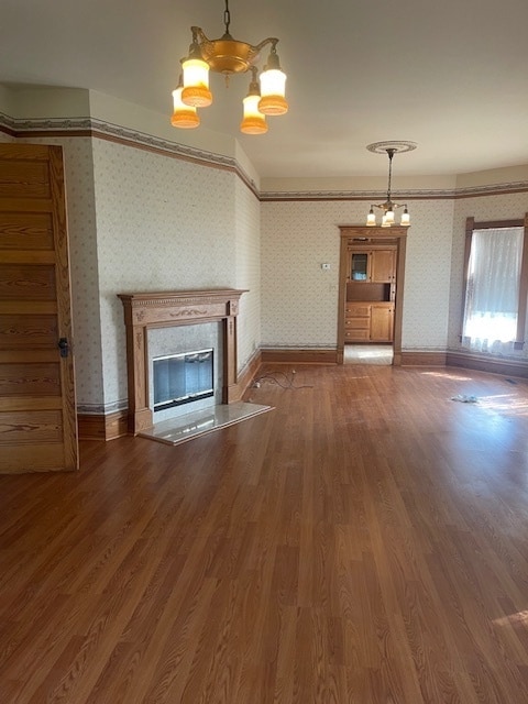 unfurnished living room featuring a notable chandelier, ornamental molding, and hardwood / wood-style flooring