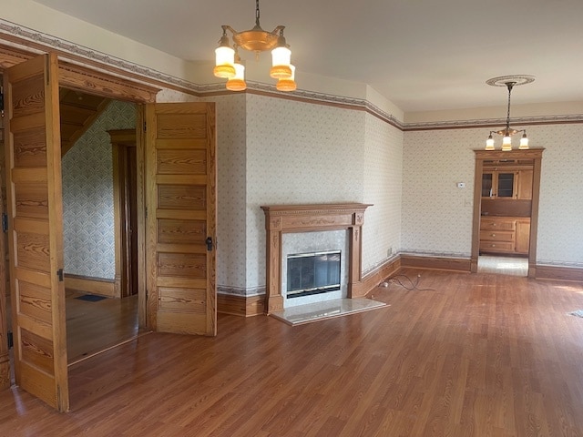 unfurnished living room with hardwood / wood-style flooring and a chandelier