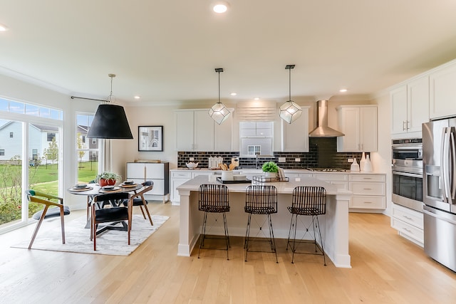 kitchen featuring a healthy amount of sunlight, wall chimney exhaust hood, a kitchen island, and white cabinets