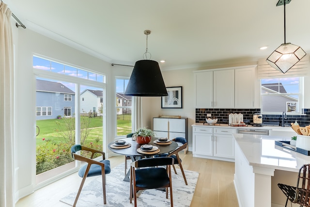 kitchen with white cabinetry, tasteful backsplash, light wood-type flooring, and pendant lighting