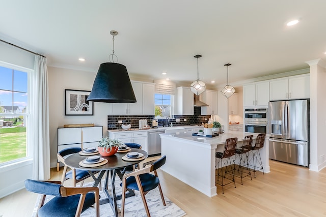 kitchen featuring white cabinetry, stainless steel appliances, a center island, and decorative light fixtures