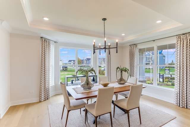 dining area featuring light hardwood / wood-style floors, a notable chandelier, and a tray ceiling