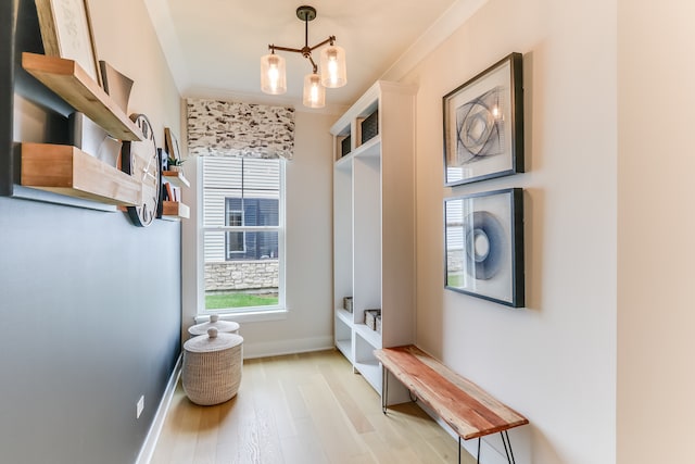 mudroom with ornamental molding, an inviting chandelier, and light wood-type flooring