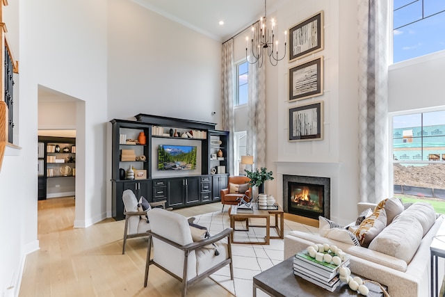 living room featuring light hardwood / wood-style floors, plenty of natural light, an inviting chandelier, and a high ceiling