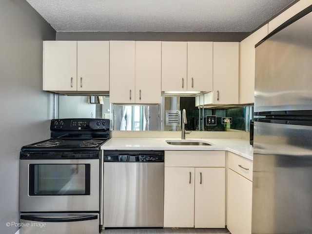 kitchen featuring a textured ceiling, appliances with stainless steel finishes, sink, and white cabinets