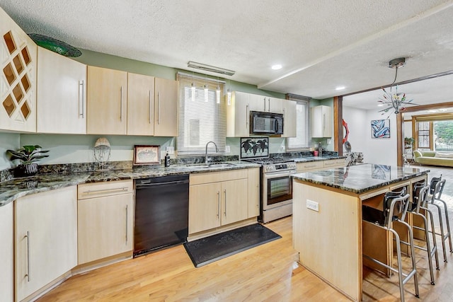 kitchen featuring black appliances, sink, a kitchen island, a textured ceiling, and light hardwood / wood-style flooring