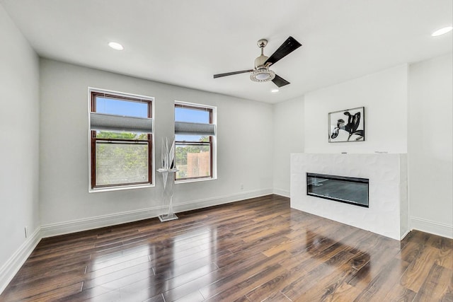 unfurnished living room with ceiling fan, a premium fireplace, and dark hardwood / wood-style flooring