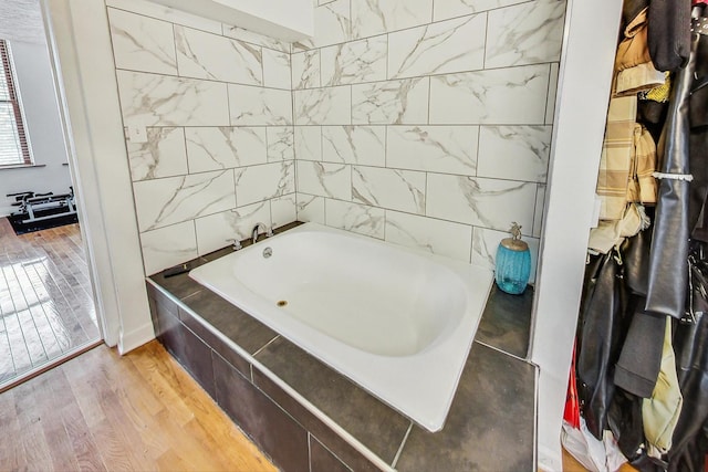 bathroom featuring a relaxing tiled tub and hardwood / wood-style flooring