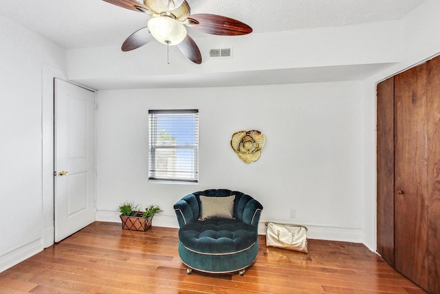 sitting room with ceiling fan and hardwood / wood-style flooring