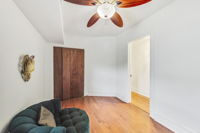 living area with light hardwood / wood-style flooring, a textured ceiling, and ceiling fan