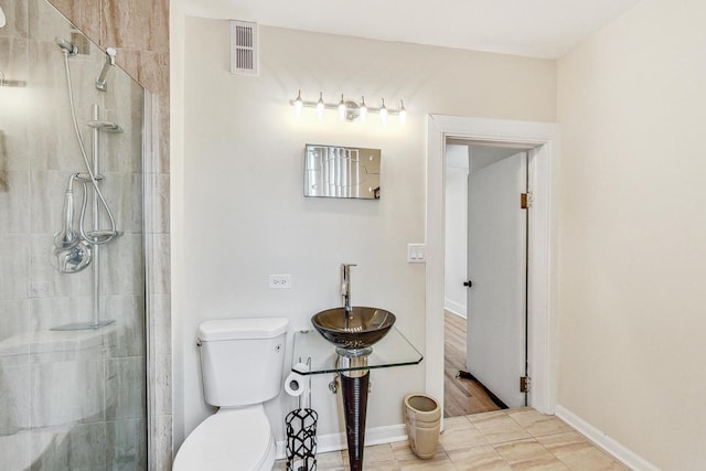 bathroom featuring toilet, an enclosed shower, sink, and wood-type flooring