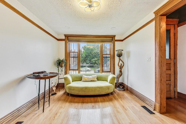 sitting room featuring crown molding, a textured ceiling, and light wood-type flooring