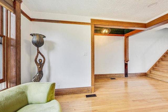 interior space with ornamental molding, hardwood / wood-style floors, and a textured ceiling