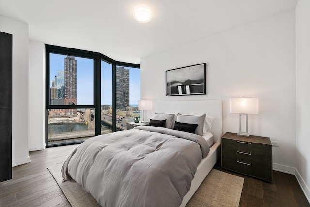 bedroom featuring expansive windows, a water view, and dark hardwood / wood-style floors