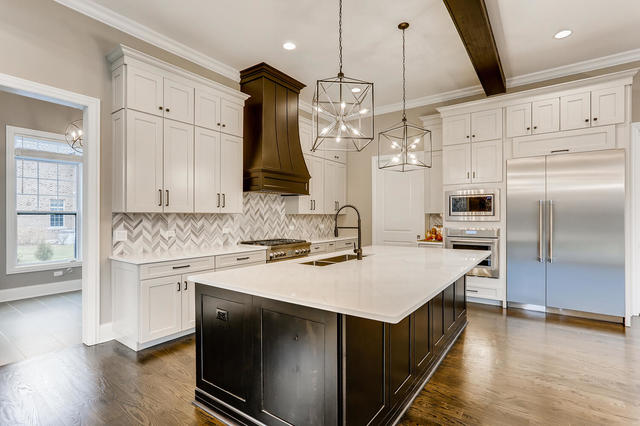 kitchen with white cabinetry, a kitchen island with sink, beamed ceiling, and built in appliances