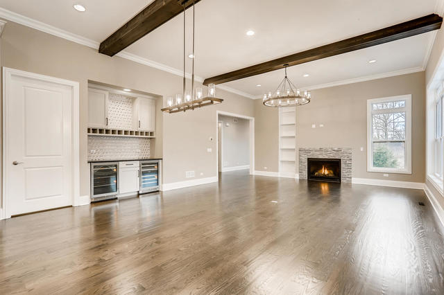 2 Alexandra Dr, Mettawa, IL 60048 - unfurnished living room with wine cooler, beamed ceiling, a dry bar, a lit fireplace, and baseboards