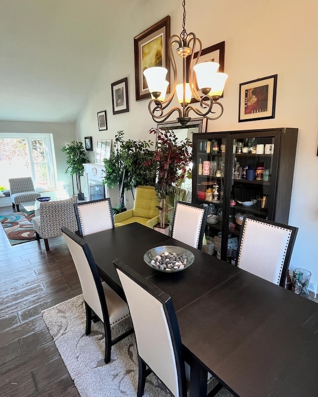 dining area with lofted ceiling, a chandelier, and dark hardwood / wood-style flooring