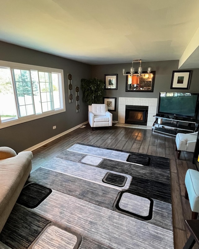 living room with a tile fireplace and dark hardwood / wood-style flooring